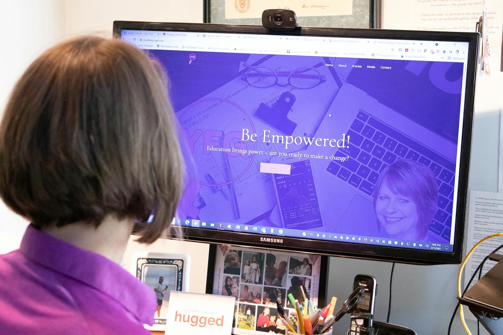 Woman in purple blouse viewing educational website on office computer monitor.